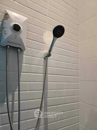 Modern bathroom with sleek white tiles and a wall-mounted shower head.