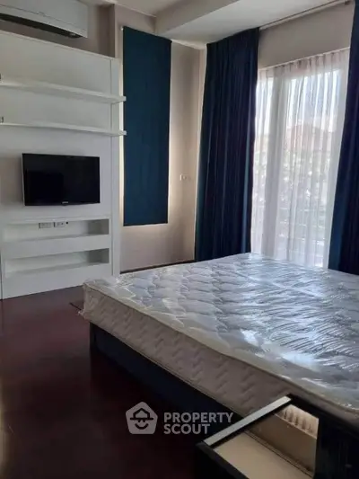 Modern bedroom with large window and built-in TV, featuring sleek design and natural light.