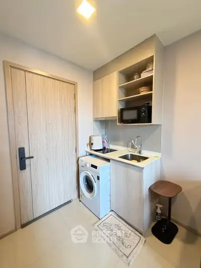 Compact modern kitchen with washing machine and microwave in cozy apartment.