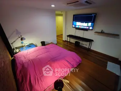 Cozy bedroom with modern decor and wall-mounted TV, perfect for relaxation.