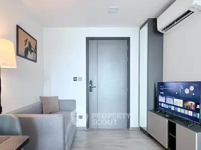 Modern living room with sleek furniture and wall-mounted TV, featuring minimalist decor and air conditioning.