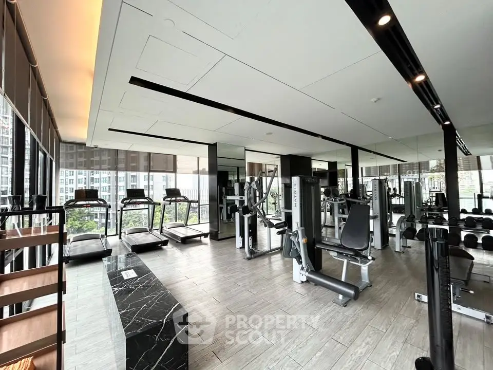 Modern gym with state-of-the-art equipment and city view in luxury residential building.