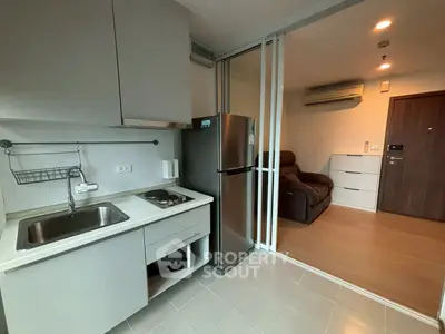 Modern compact kitchen with stainless steel fridge and cozy living area