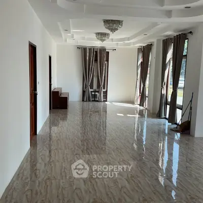 Spacious and elegant living room with large windows and modern ceiling design.