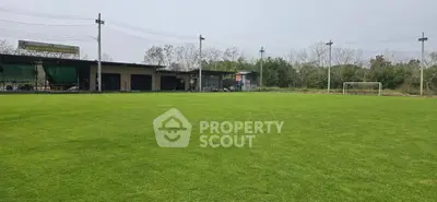 Expansive green field with goalpost, perfect for sports and recreation in serene setting.