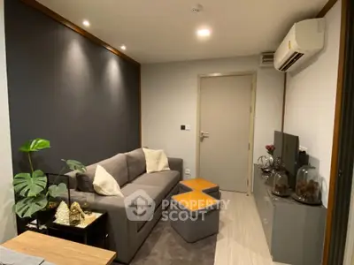 Modern living room with sleek gray sofa, stylish decor, and air conditioning unit.