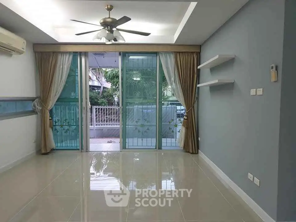 Spacious living room with large windows and modern ceiling fan in a stylish apartment.