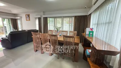 Spacious living and dining area with elegant wooden furniture and large windows.