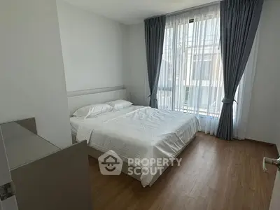 Bright and airy bedroom with large window and elegant curtains, perfect for relaxation.