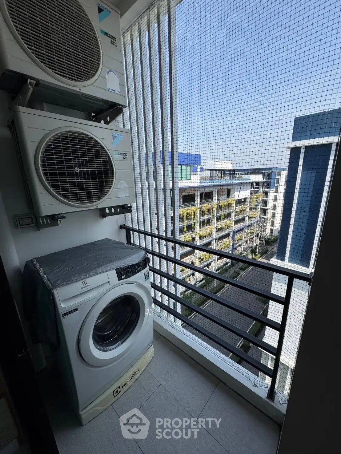 Modern apartment balcony with washing machine and air conditioning units, offering a city view.
