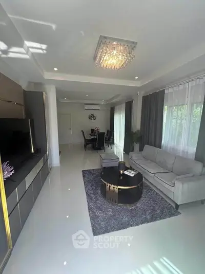 Elegant living room with modern decor and dining area, featuring a plush sofa and stylish lighting.