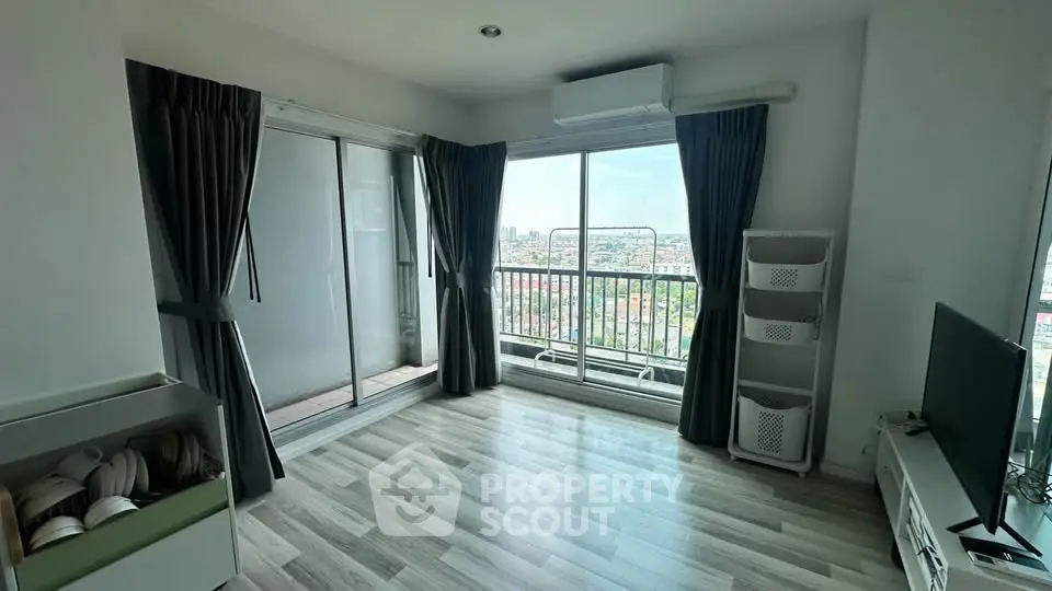 Spacious living room with large windows and balcony offering stunning city views.