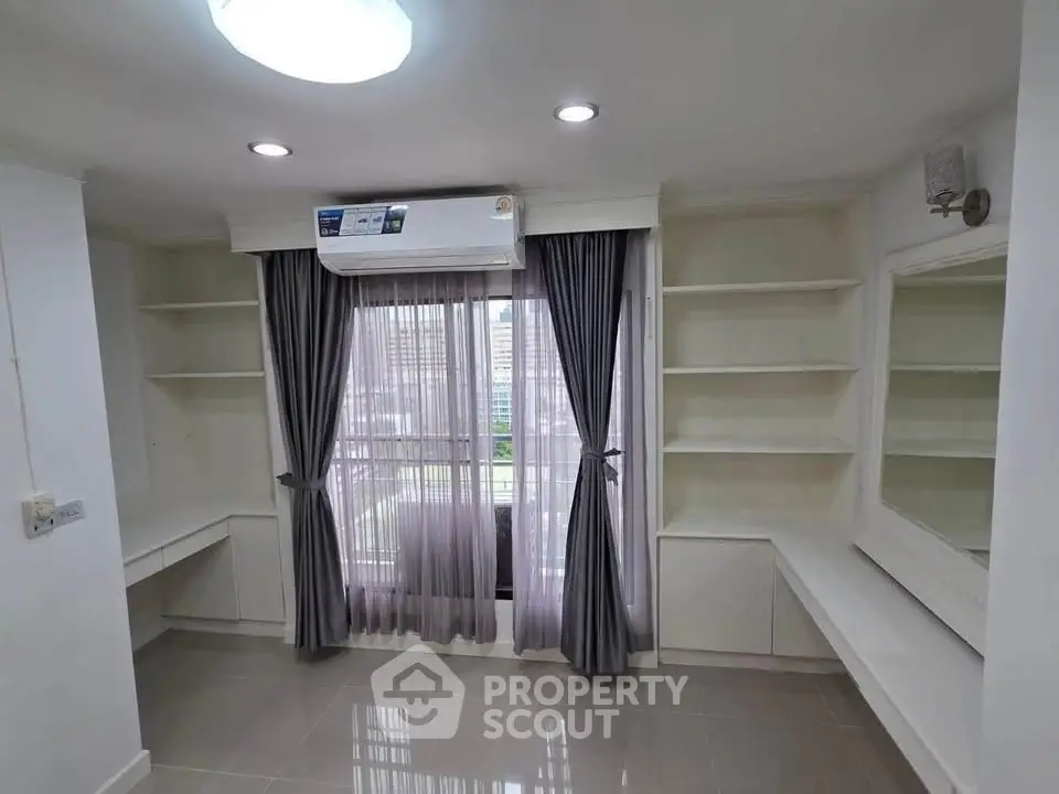 Modern room with built-in shelves and large window offering city view, perfect for a home office or study.