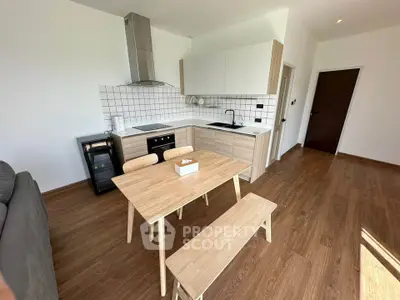 Modern kitchen with sleek design and wooden flooring, featuring open layout and dining area.