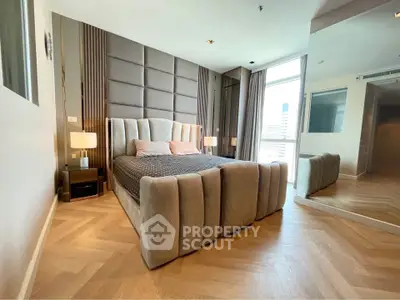 Luxurious modern bedroom with elegant decor and large mirror reflecting natural light.