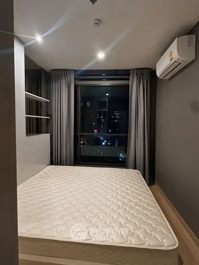 Modern bedroom with city view, featuring a large window and air conditioning.