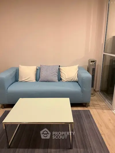 Modern living room with blue sofa and sleek coffee table on stylish rug.