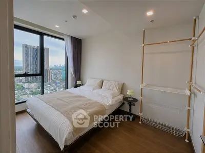 Modern bedroom with city view, featuring minimalist design and large window for natural light.