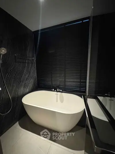 Luxurious modern bathroom with elegant freestanding bathtub and sleek black accents.