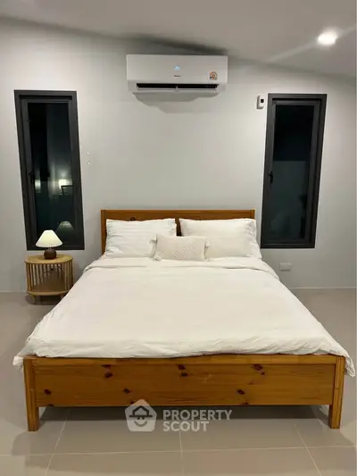 Modern bedroom with wooden bed frame, white bedding, and air conditioning unit.