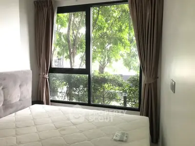 Bright bedroom with large window and lush greenery view