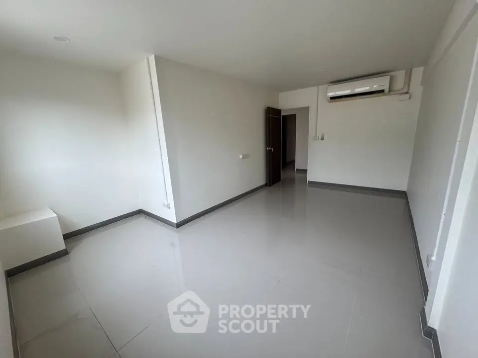 Spacious unfurnished room with sleek tiled flooring and air conditioning, perfect for customization.