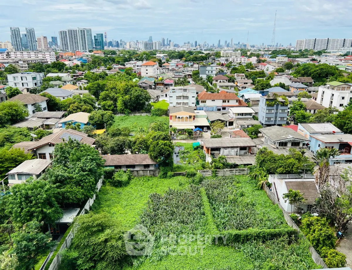 Aerial view of lush green residential area with city skyline in the background, showcasing urban and suburban blend.