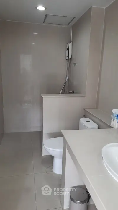 Modern bathroom with sleek design and neutral tones, featuring a shower and toilet.