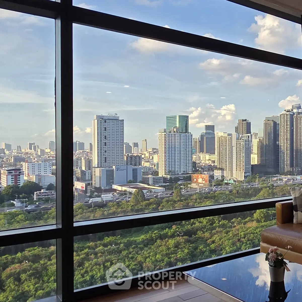 Stunning cityscape view from a modern high-rise apartment window, showcasing urban skyline and lush greenery.