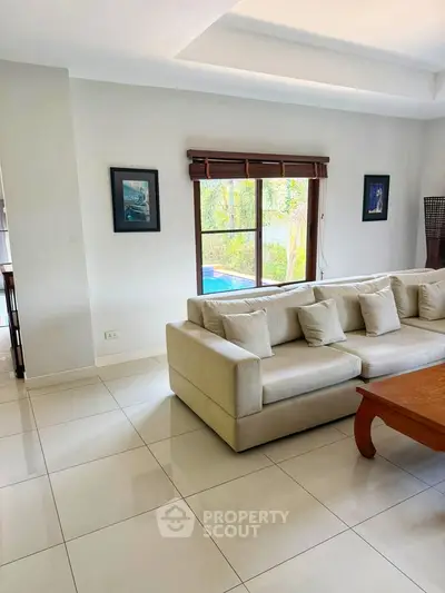 Spacious living room with elegant sofa and pool view, perfect for relaxation and entertaining.