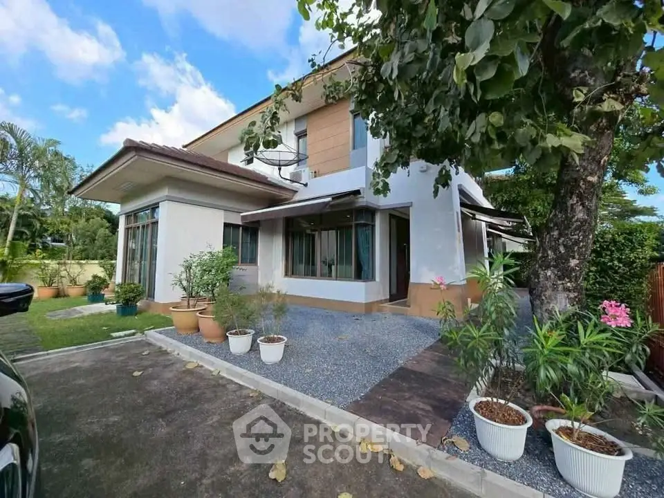 Charming two-story house with lush garden and modern exterior design.