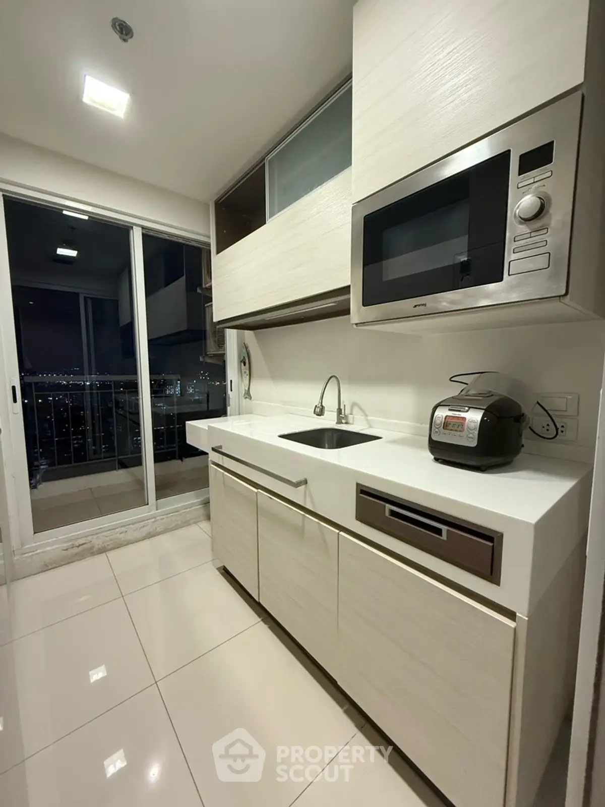 Modern kitchen with sleek cabinetry and balcony view