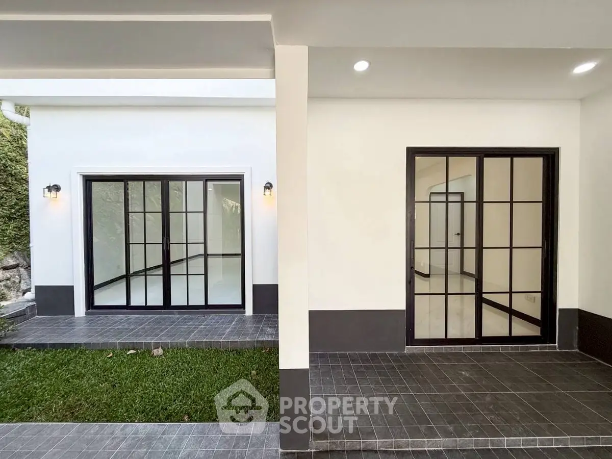 Modern home exterior with sleek sliding glass doors and tiled patio area.