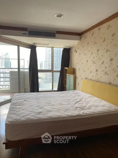 Spacious bedroom with large windows and city view, featuring modern decor and ample natural light.