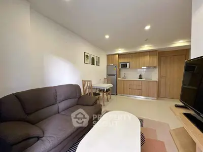Modern open-layout living room with kitchen, cozy sofa, and dining area in stylish apartment.