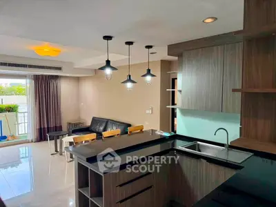 Modern open-layout kitchen and living room with stylish lighting and balcony view.