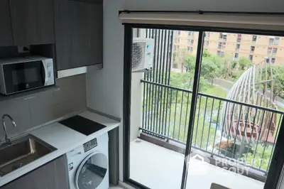 Modern kitchen with balcony view, featuring sleek appliances and ample natural light.