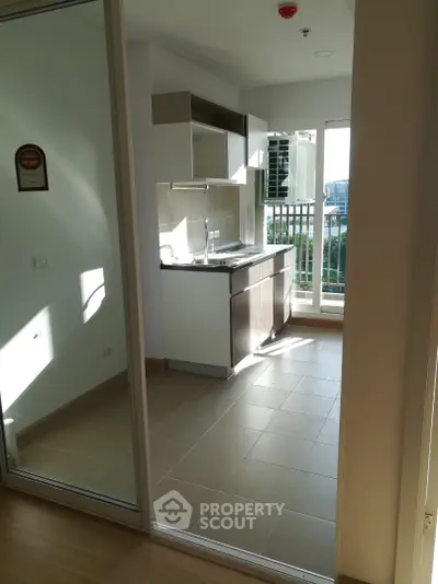 Modern kitchen with sleek cabinetry and large windows offering natural light and a view of the outdoors.