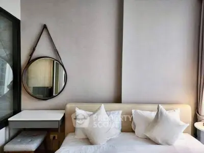 Modern bedroom with stylish round mirror and cozy white bedding