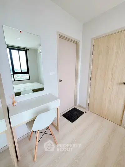 Modern bedroom corner with stylish vanity and chair, bright natural light from window.