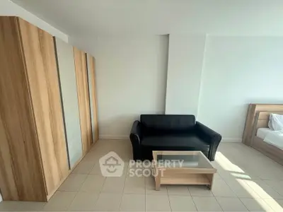 Modern minimalist bedroom with sleek black sofa and wooden furniture, perfect for urban living.