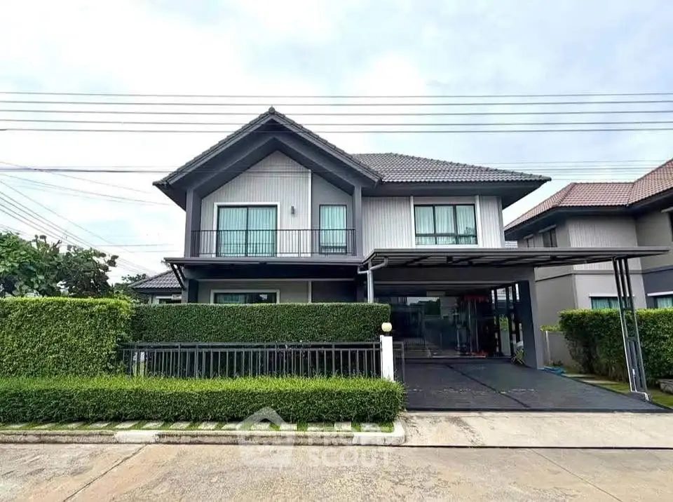 Modern two-story house with manicured hedges and spacious driveway in a serene neighborhood.