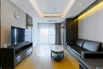Modern living room with sleek furniture and large TV, featuring elegant lighting and wooden flooring.