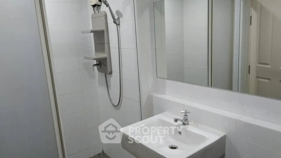 Modern bathroom with sleek white sink and shower area, perfect for minimalist living.