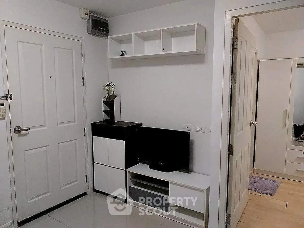 Modern apartment entrance with sleek storage and TV unit, showcasing minimalist design.