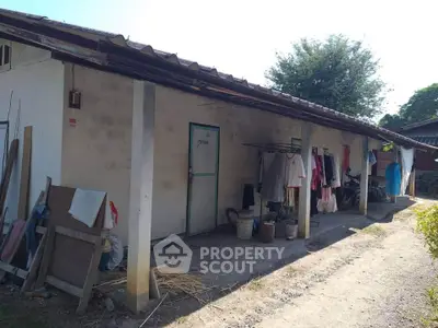 Rustic exterior view of a rural building with clothesline and garden path.