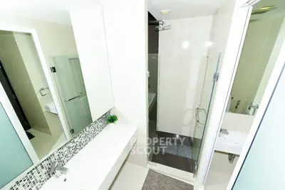 Modern bathroom with glass shower and sleek vanity in contemporary apartment.