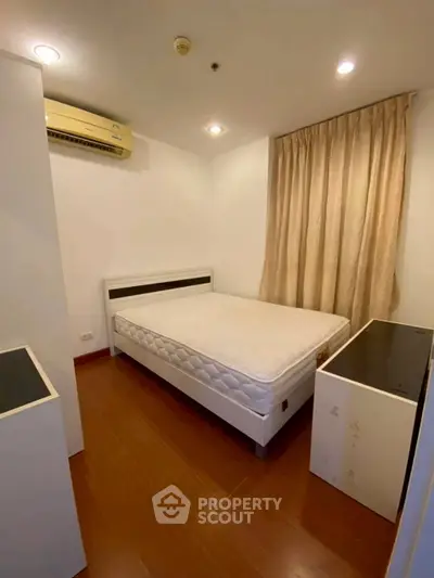 Cozy bedroom with wooden flooring and air conditioning in modern apartment