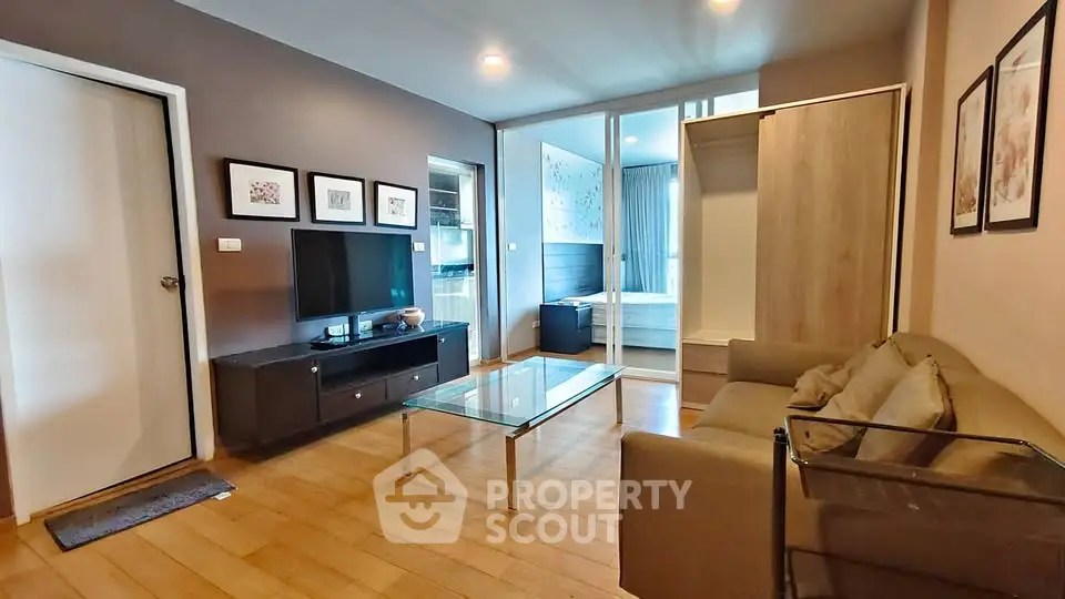 Modern living room with glass coffee table and cozy sofa, open view to bedroom