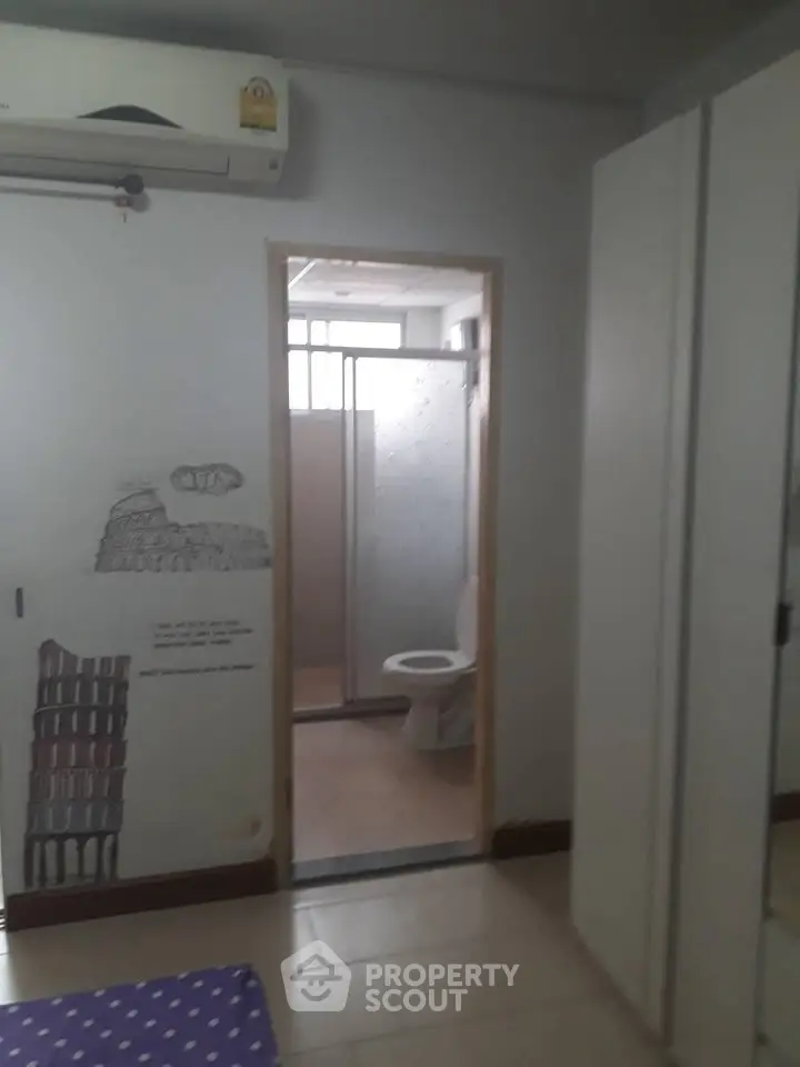 Cozy bedroom with ensuite bathroom, featuring air conditioning and modern wardrobe.